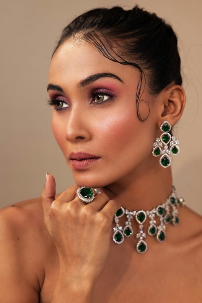 A stunning portrait showcasing a woman adorned with emerald jewelry, highlighting elegance and beauty.